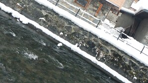 Eine Holzhütte mit Steinunterbau, einem Balkon und Blick auf einen Fluss.