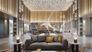 A spacious lobby with a modern sofa, wooden tables, and a unique hanging light fixture.