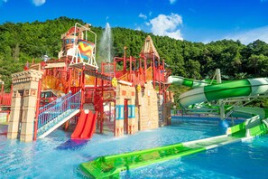 Parque acuático con un tobogán gigante, chorros de agua y una piscina.