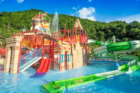 A water park with a large water slide, a water jet, and a pool.