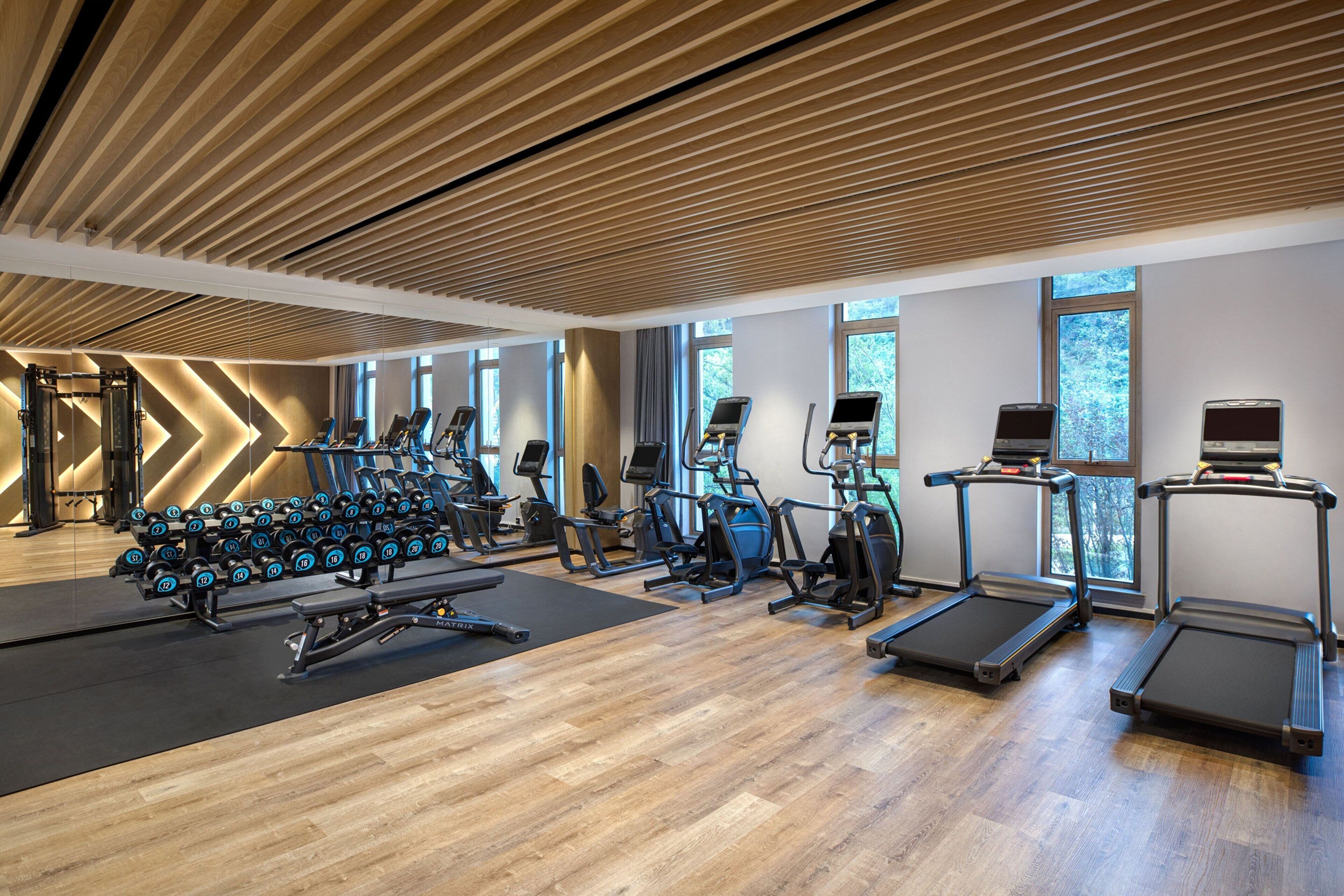Ein modernes Fitnessstudio mit Laufbändern, Crosstrainern und Kurzhanteln.