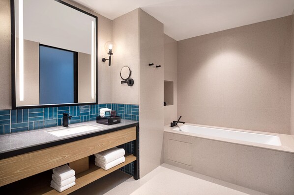 Un baño moderno con un espejo grande, dos lavamanos, una bañera y un salpicadero de azulejos azules.
