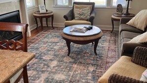 A living room with a fireplace, a round coffee table, a sofa, and two armchairs. - Dog Friendly Townhome in the heart of Stone Harbor (Stone Harbor)