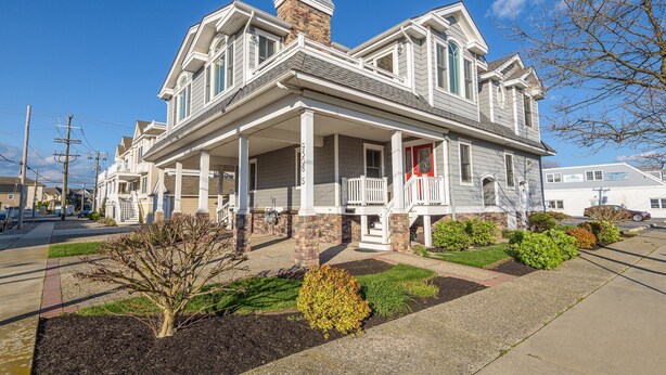 A two-story house with a porch, brick foundation, and a chimney. - Dog Friendly Townhome in the heart of Stone Harbor (Stone Harbor)