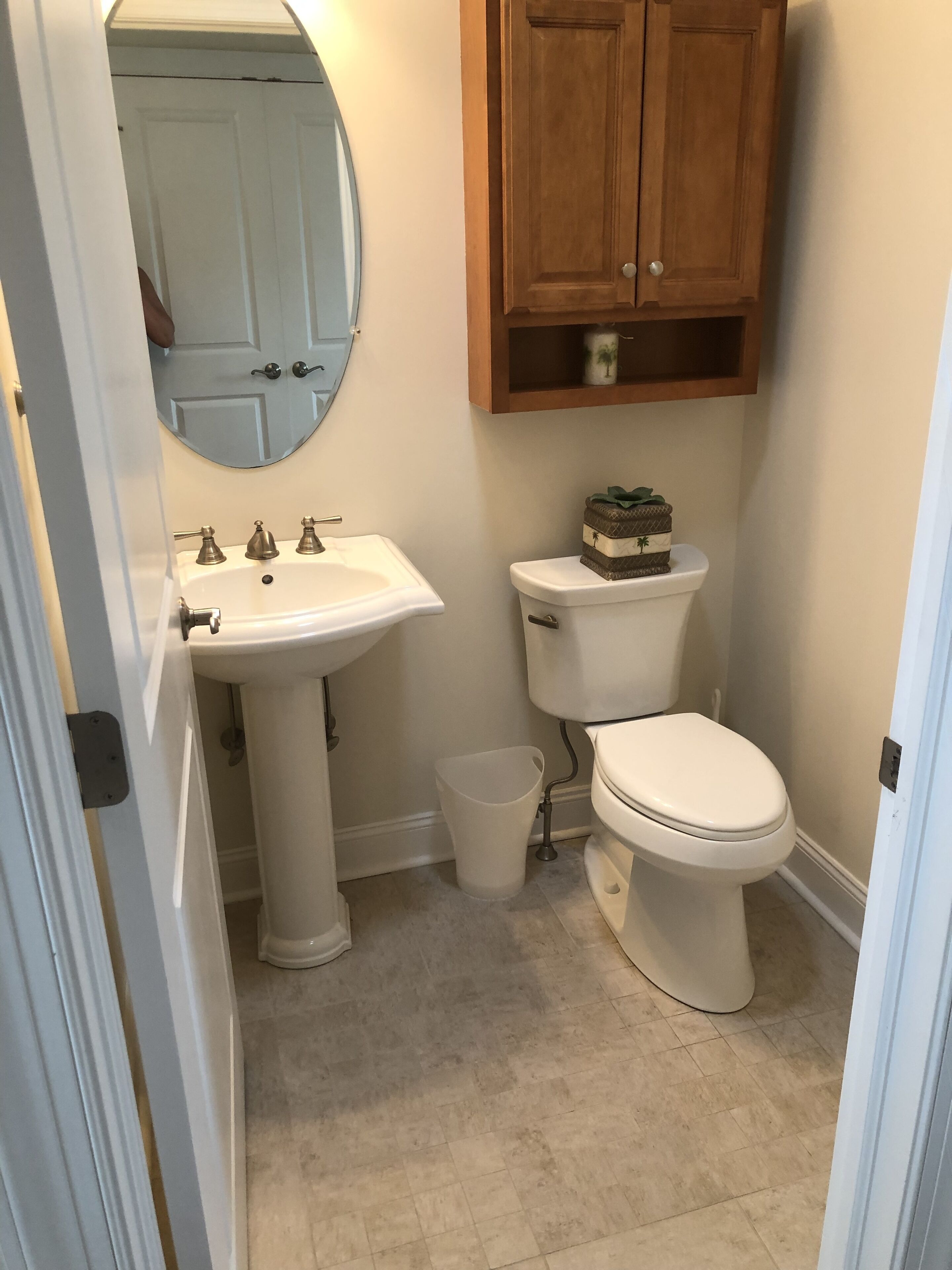 A bathroom with a pedestal sink, a toilet, and a wooden cabinet above the toilet. - Dog Friendly Townhome in the heart of Stone Harbor (Stone Harbor)