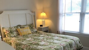 A bedroom with a bed, a nightstand, a lamp, and a window with blinds. - Dog Friendly Townhome in the heart of Stone Harbor (Stone Harbor)