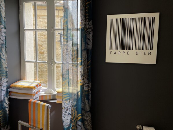 A bathroom with a window, towels, and a wall-mounted barcode sign.