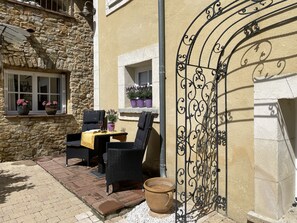 A stone building with a balcony, outdoor seating, and potted plants.