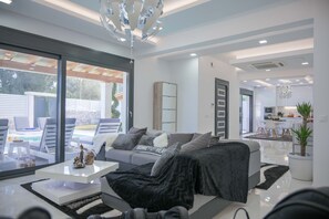 A modern living room with a sofa, coffee table, and a view of a pool and outdoor seating area.