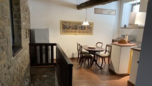 A dining area with a wooden table and chairs, a hanging light fixture, and a wall-mounted painting.