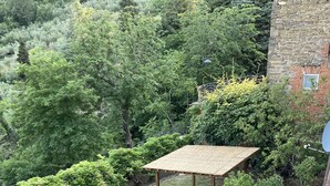 A backyard with a pergola, a table with chairs, a small garden, and a brick wall.