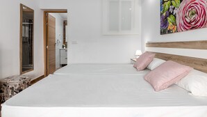 A bedroom with a large bed, a wooden headboard, a nightstand, and a wall-mounted painting.