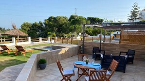 An outdoor patio with a pool, lounge chairs, and a dining area with tables and chairs.