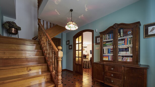 A wooden staircase with a chandelier, a hexagonal tiled floor, and a wooden bookcase with books. - Finca Engracia Tranquilidad, Comodidad y Descanso (Cudillero)