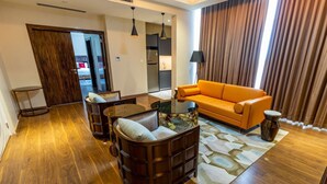 A modern living room with a wooden floor, a sofa, a coffee table, and a lamp. - Hôtel Fleur de Lys Point E (Dakar)