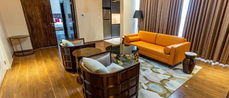 Un salon moderne avec un plancher en bois, un canapé, une table basse et une lampe.
