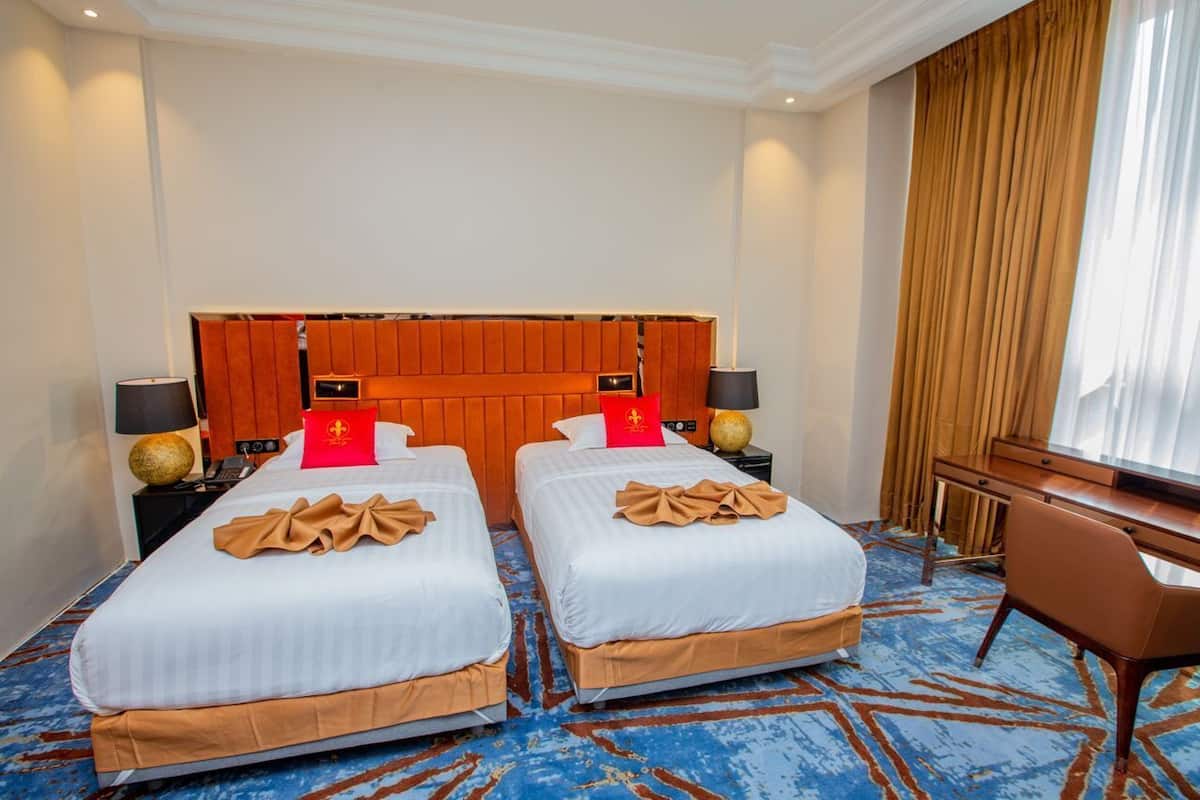 Habitación de hotel con dos camas, un cabecero de madera, un escritorio y una silla.