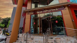 A hotel with a modern design, featuring a prominent red and beige color scheme, large glass windows, and a visible entrance with a sign. - Hôtel Fleur de Lys Point E (Dakar)