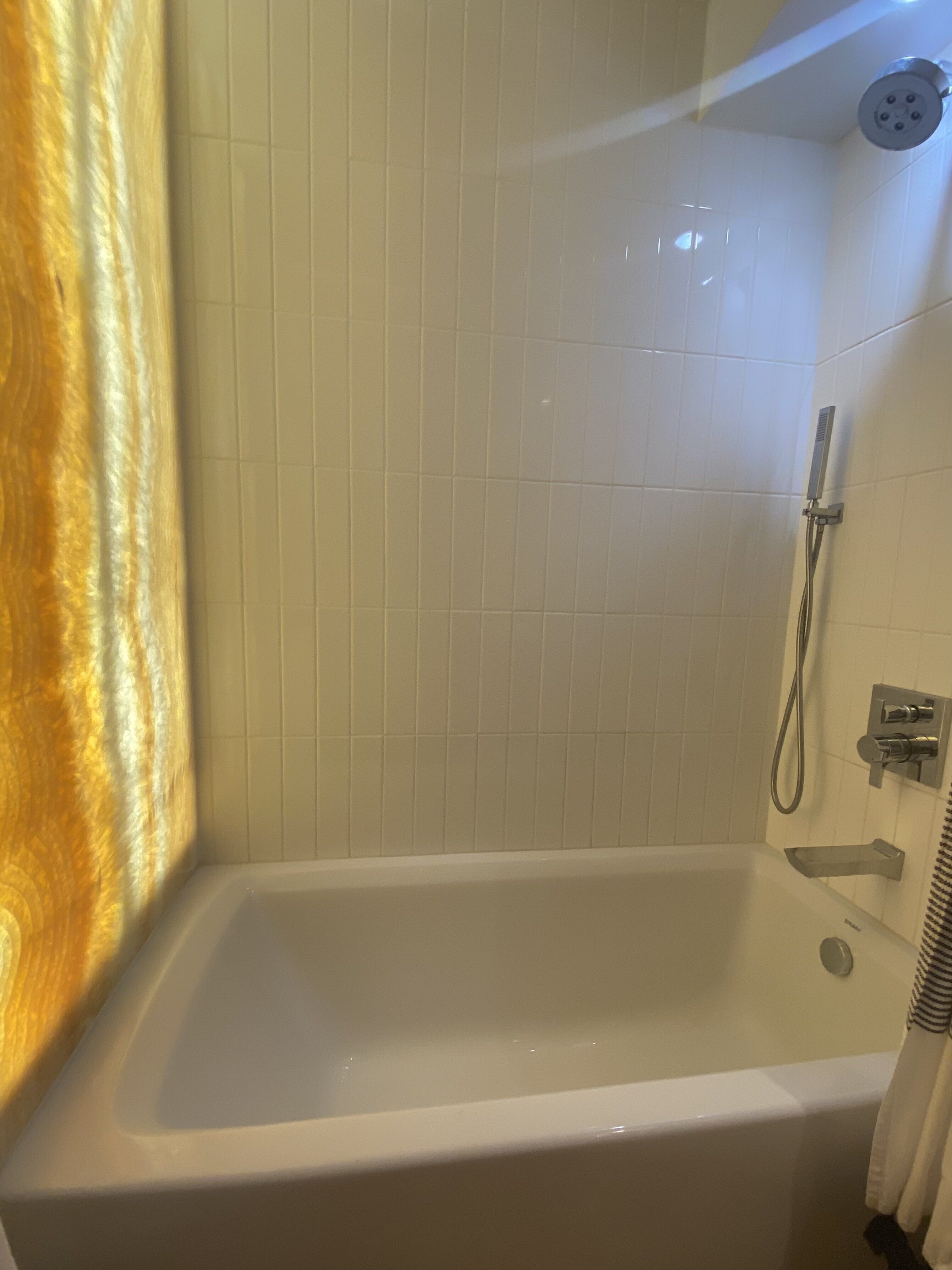 A bathroom with a bathtub, a shower, and a towel rack.
