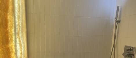 A bathroom with a bathtub, a shower, and a towel rack.