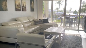 Un salon moderne avec un canapé en cuir blanc, une table basse en verre et un ventilateur de plafond.