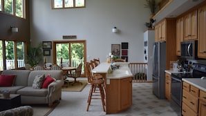 Une cuisine spacieuse dotée de meubles en bois, d’un grand îlot central et d’un coin repas avec des chaises et une table.