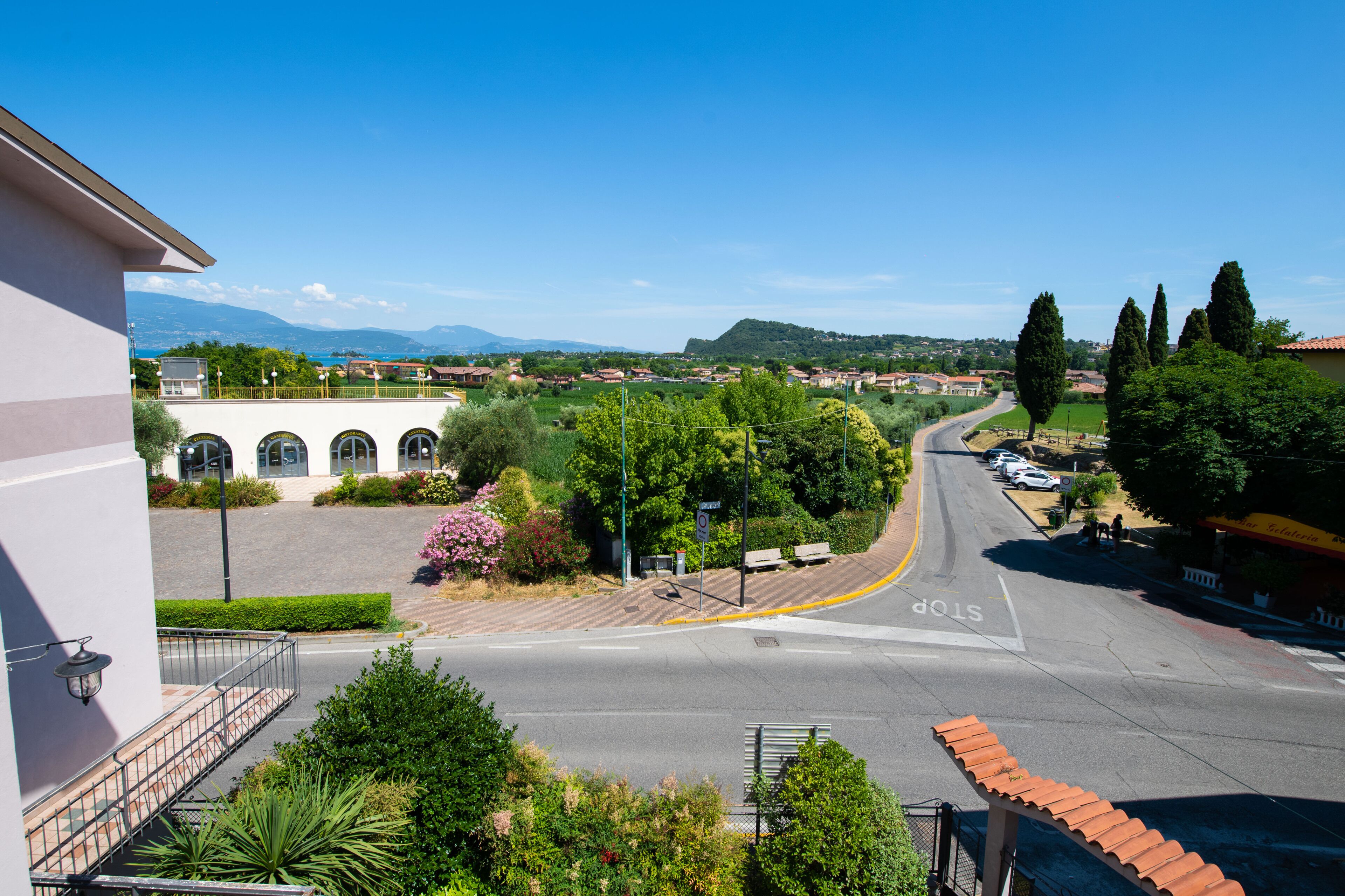 Une vue de rue avec une route dégagée, un panneau de signalisation indiquant un arrêt obligatoire et un immeuble doté d’un balcon.