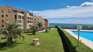 Ein Hotel mit Pool, gepflegtem Rasen und Meerblick.