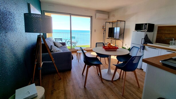 Eine moderne Küche mit Essbereich, einer Couch und einem Balkon mit Meerblick.