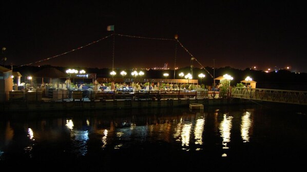 A waterfront restaurant with outdoor seating, a bridge, and a view of the water. - Beach Luxury Hotel (Karachi)