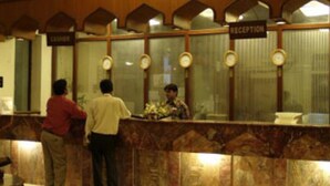 A reception area with a marble counter, a reception desk, and a clock on the wall. - Beach Luxury Hotel (Karachi)