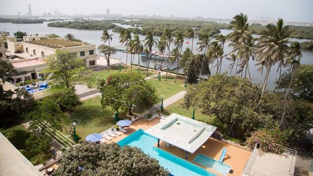 A pool area with a view of a river and palm trees. - Beach Luxury Hotel (Karachi)
