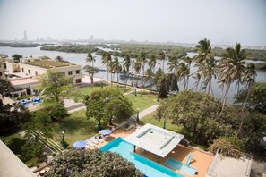 A pool area with a view of a river and palm trees. - Beach Luxury Hotel (Karachi)