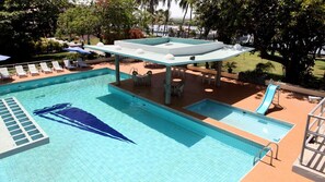A swimming pool with lounge chairs, a sun shelter, and a slide. - Beach Luxury Hotel (Karachi)