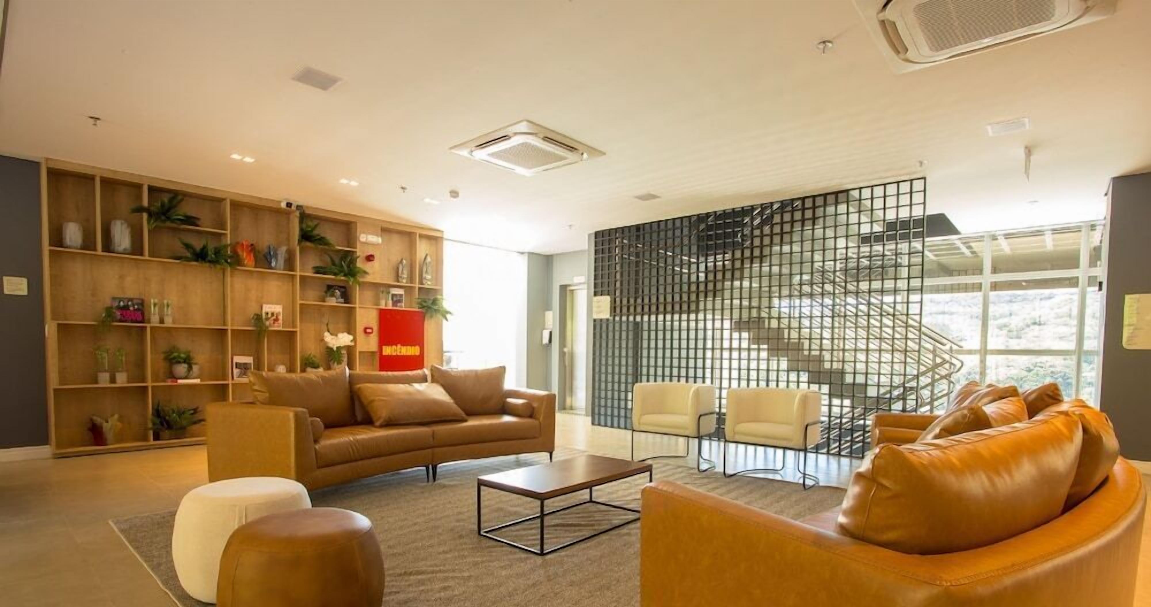 Una sala de estar moderna con un sofá, sillones, una mesa de centro y una estantería llena de objetos decorativos.