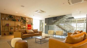 Una sala de estar moderna con un sofá, sillones, una mesa de centro y una estantería llena de objetos decorativos.