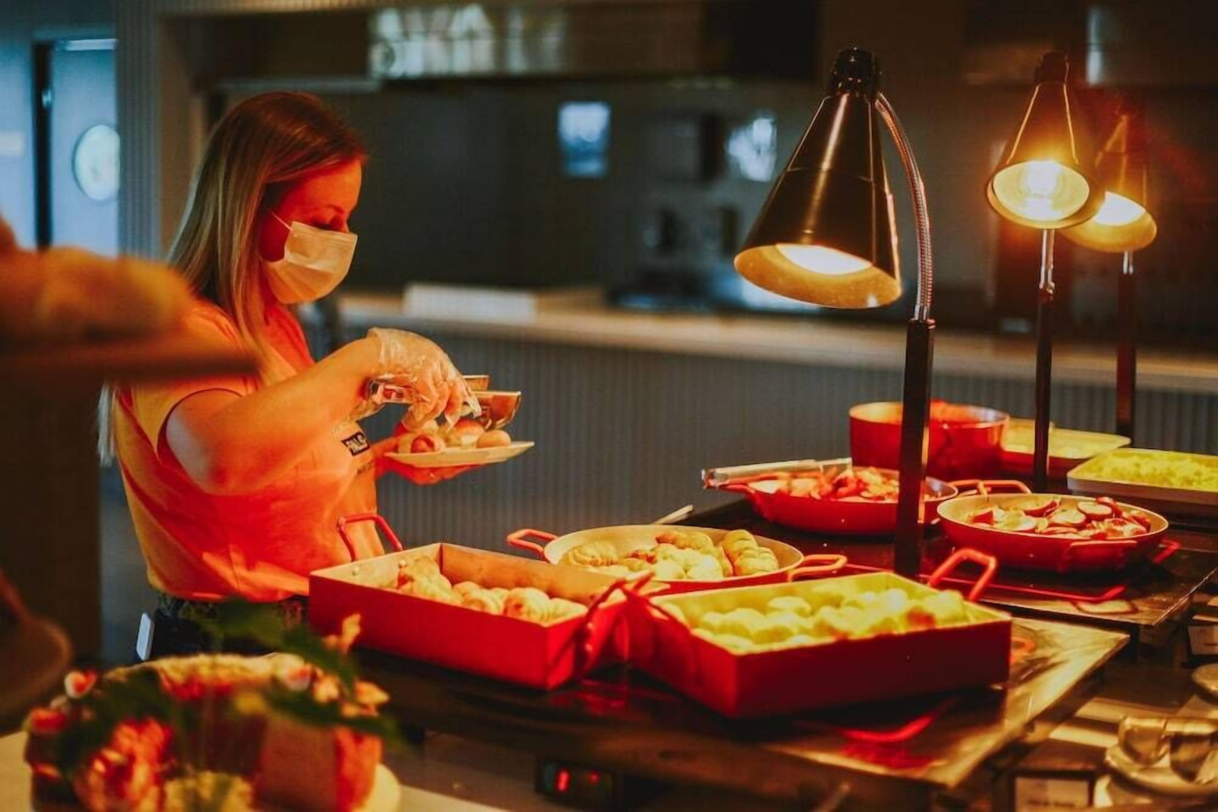 Una mesa de buffet con diversos alimentos y una persona sirviendo.