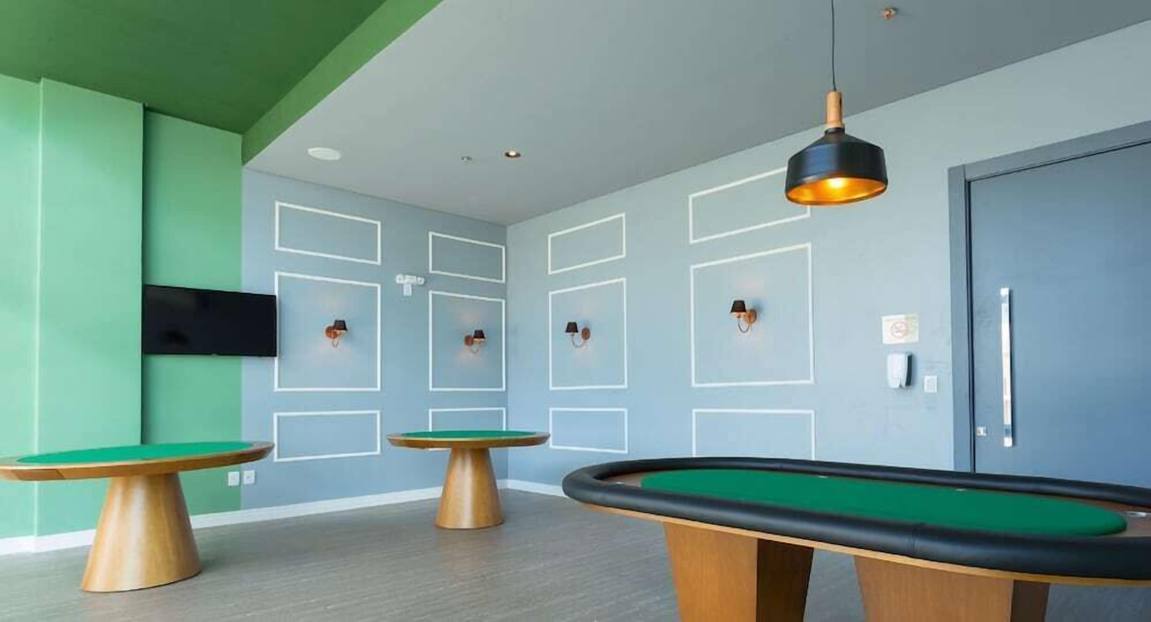 Una habitación con tres mesas de billar, una pared verde y una puerta azul.