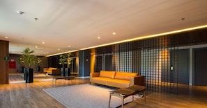 A modern lobby with a sofa, chairs, a coffee table, and a decorative partition.