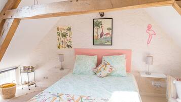 A bedroom with a sloped ceiling, a bed with floral bedding, a pink headboard, and a small side table.