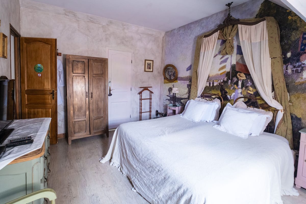 Une chambre à coucher avec un lit, une armoire en bois et une fresque murale.