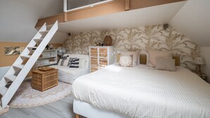 Un dormitorio con cama alta, una escalera, un aparador de madera y un papel tapiz estampado.