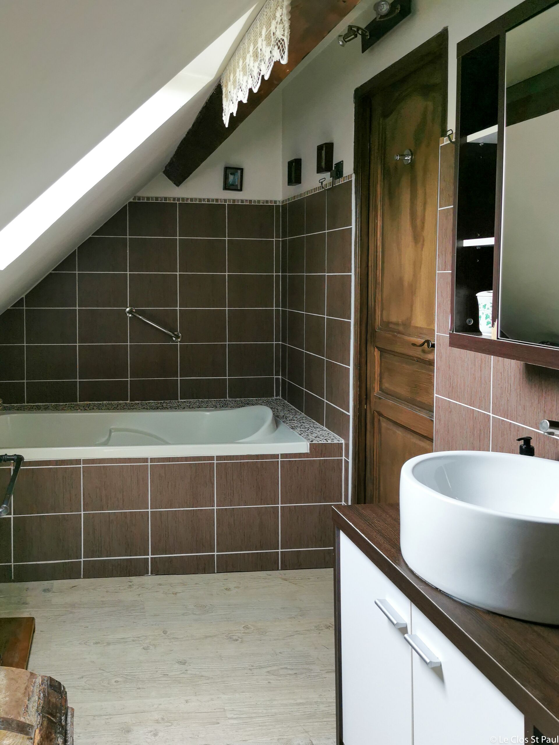 Une salle de bain avec une baignoire, un lavabo et une porte en bois.