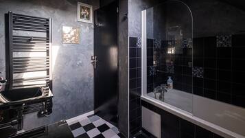 Un baño moderno con piso a cuadros blanco y negro, ducha con cerramiento de vidrio y un espejo grande.