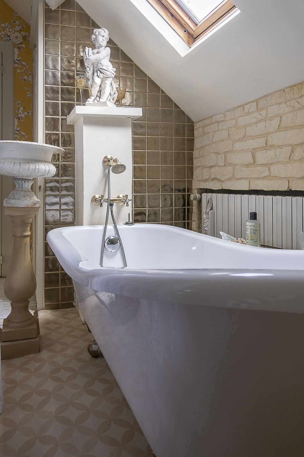 A bathroom with a freestanding bathtub, a pedestal basin, and a statue.