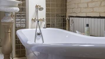 A bathroom with a freestanding bathtub, a pedestal basin, and a statue.