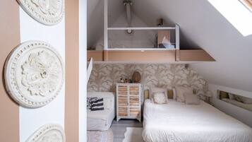 A bedroom with a loft bed, a chest of drawers, and decorative wall art.