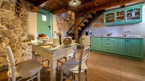 Una cocina rústica con paredes de piedra, techo de madera y armarios azul turquesa.