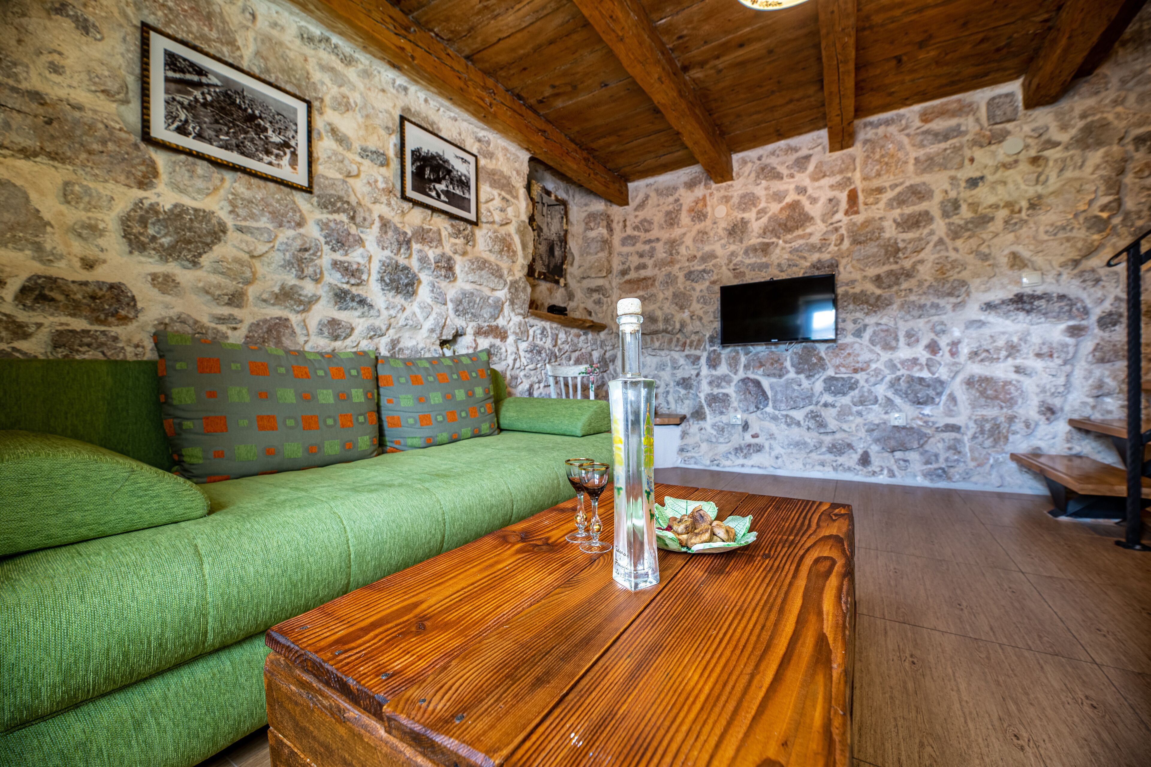 A cozy room with a green sofa, a wooden coffee table, and stone walls.