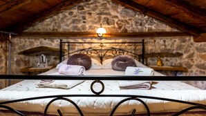 Un dormitorio rústico con pared de piedra, techo de madera y estructura de cama de metal.